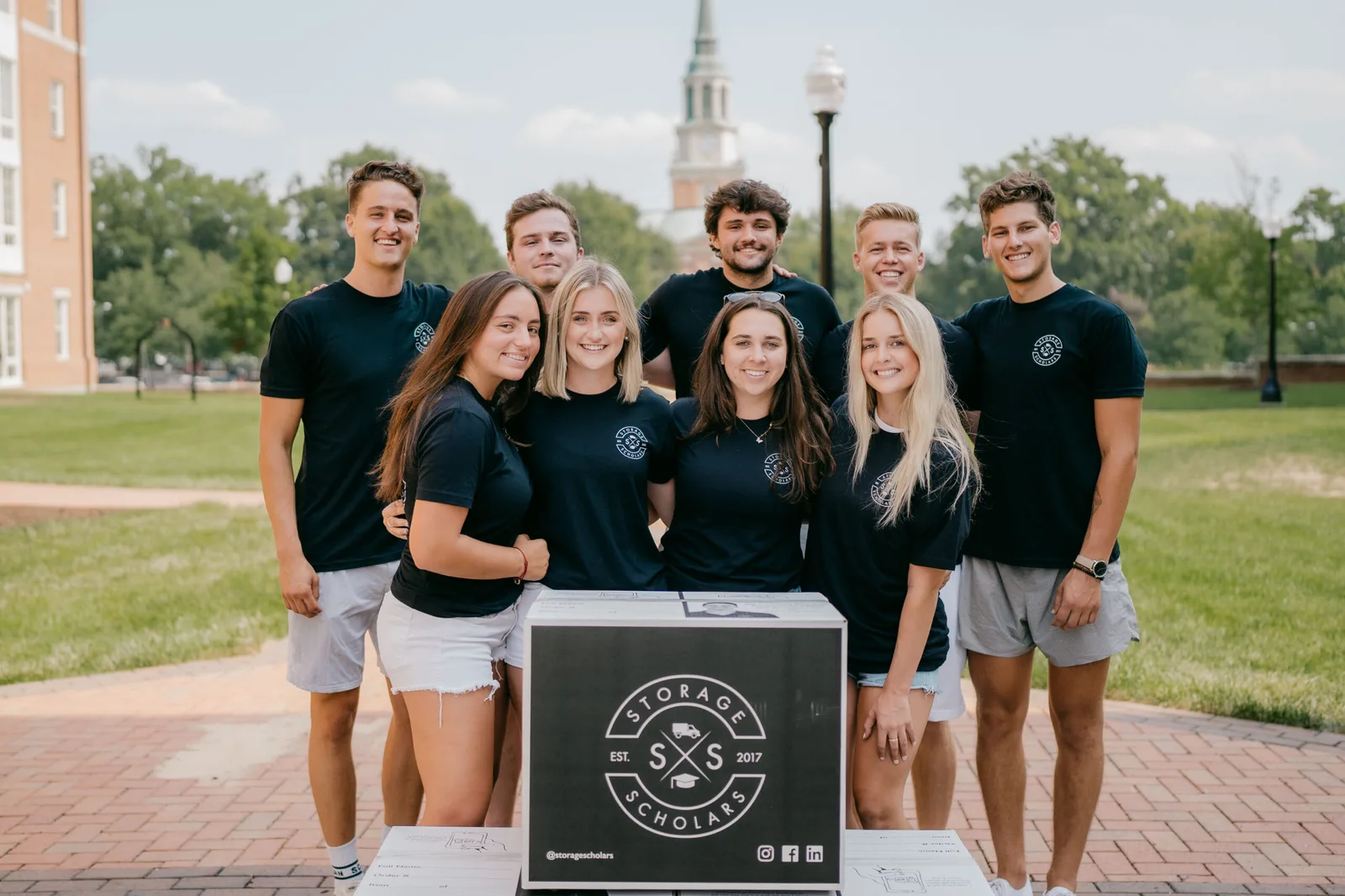 Storage Scholars student crew on a college campus with stacked branded boxes
