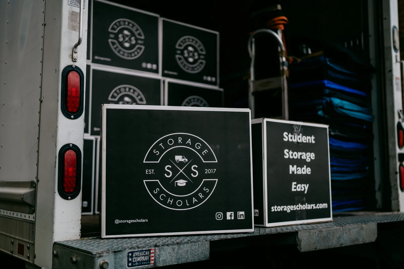 The back of a Storage Scholars truck loaded with branded boxes and moving blankets
